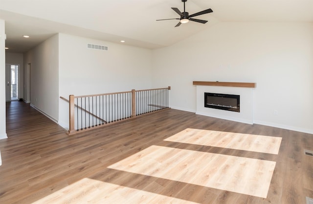 7011 Lincoln Cir, Johnston, IA 50131 - unfurnished living room featuring a ceiling fan, wood finished floors, vaulted ceiling, baseboards, and a glass covered fireplace