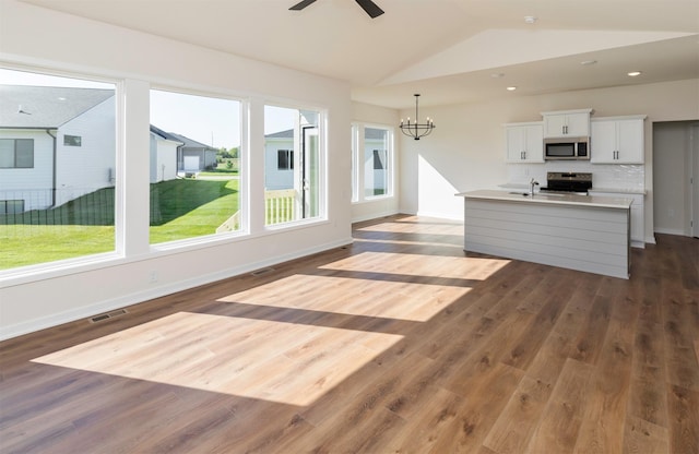 7011 Lincoln Cir, Johnston, IA 50131 - kitchen featuring appliances with stainless steel finishes, a chandelier, dark wood-style floors, a kitchen island with sink, and vaulted ceiling