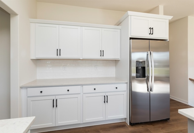 kitchen with stainless steel refrigerator with ice dispenser, dark hardwood / wood-style flooring, white cabinetry, and backsplash