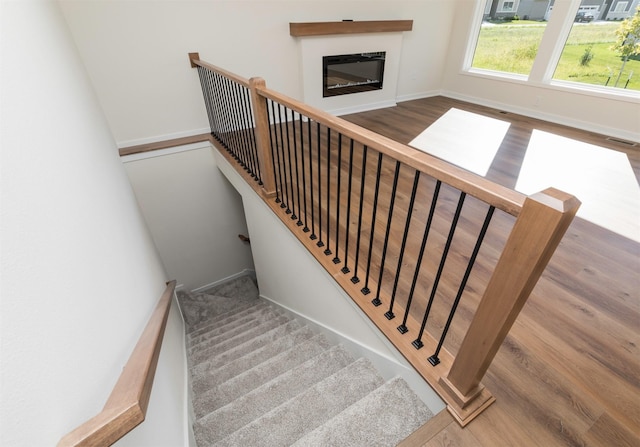 7011 Lincoln Cir, Johnston, IA 50131 - stairway with wood finished floors, baseboards, and a glass covered fireplace