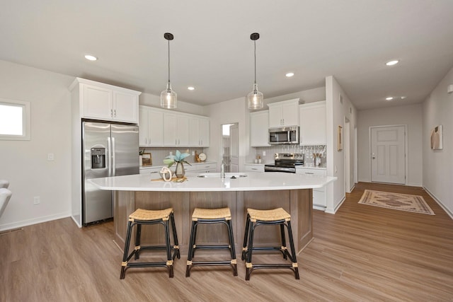 kitchen with white cabinets, sink, stainless steel appliances, and a kitchen island with sink