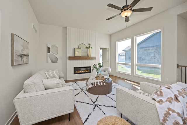 living room with ceiling fan, wood-type flooring, and a fireplace