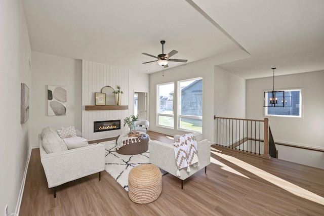 living room featuring a fireplace, ceiling fan with notable chandelier, and hardwood / wood-style flooring