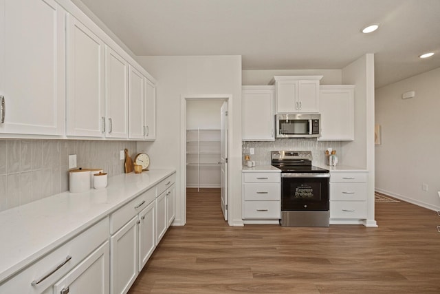 kitchen featuring tasteful backsplash, white cabinets, stainless steel appliances, and dark hardwood / wood-style floors