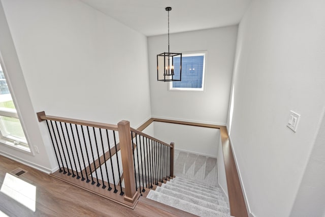 staircase with a chandelier and wood-type flooring