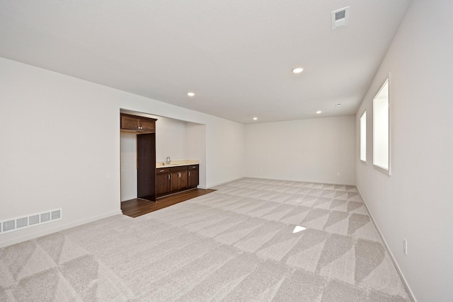 spare room featuring light colored carpet and sink