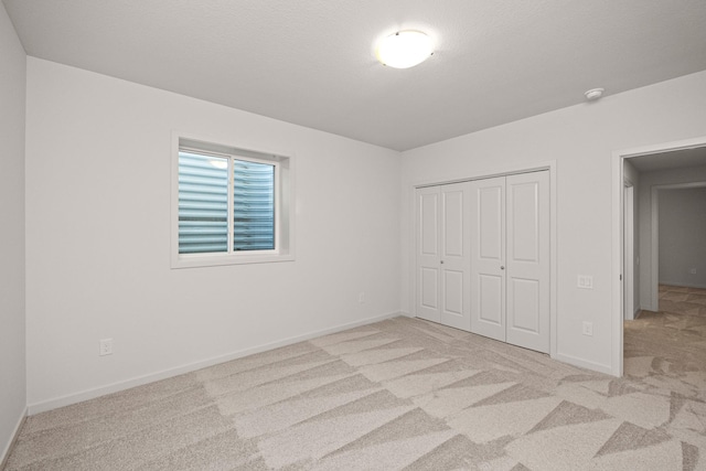 unfurnished bedroom with light colored carpet and a closet