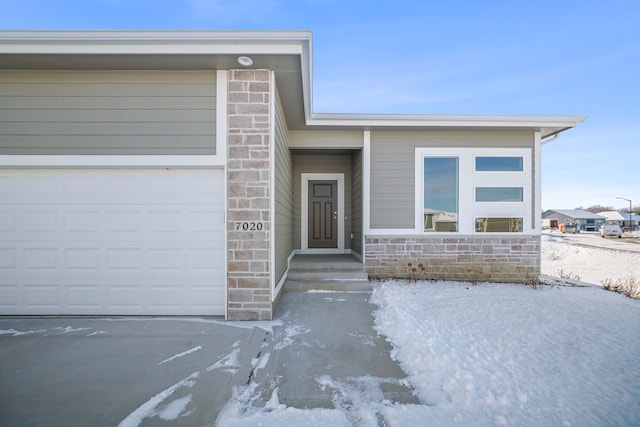 snow covered property entrance with a garage