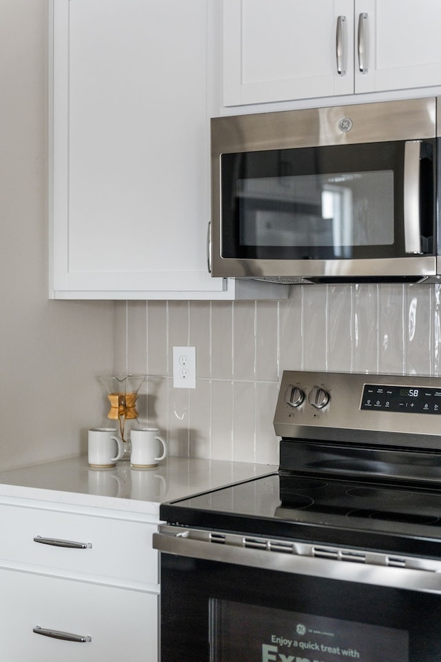 kitchen featuring white cabinets, appliances with stainless steel finishes, and tasteful backsplash