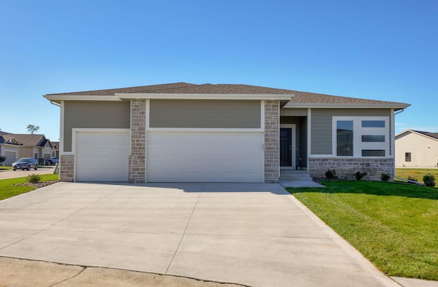 prairie-style home with a garage, roof with shingles, stone siding, a front lawn, and driveway