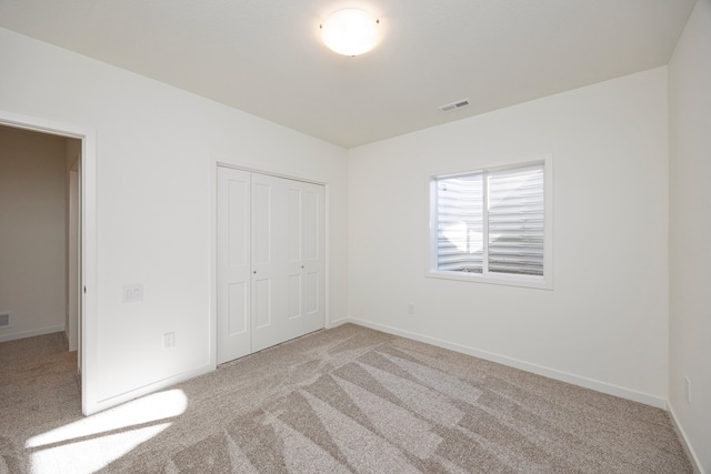 unfurnished bedroom featuring a closet and light colored carpet