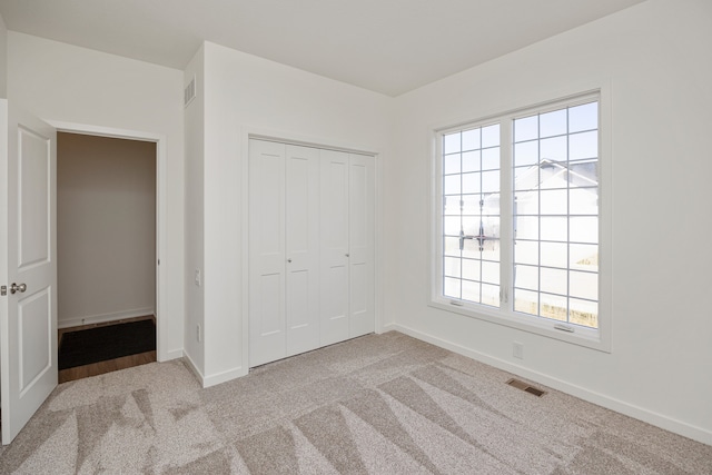 unfurnished bedroom with a closet, light colored carpet, and multiple windows