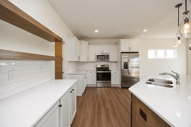 kitchen with white cabinets, appliances with stainless steel finishes, hanging light fixtures, and sink