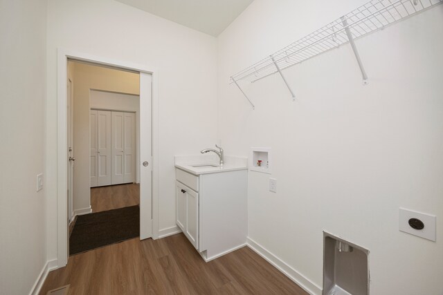 washroom with electric dryer hookup, cabinets, sink, hookup for a washing machine, and wood-type flooring