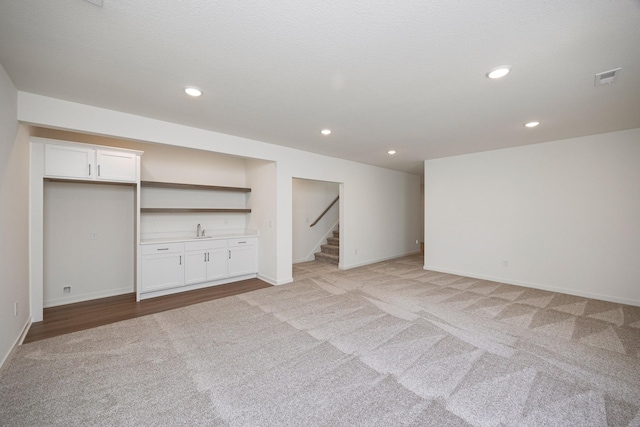8916 Beery Pl, Johnston, IA 50131 - finished basement featuring light colored carpet, bar with sink, baseboards, stairs, and recessed lighting