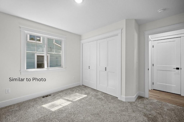 unfurnished bedroom featuring light carpet and a closet