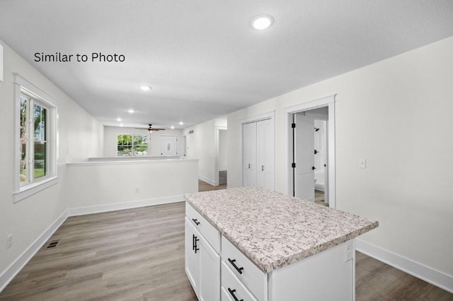 kitchen featuring hardwood / wood-style floors, a center island, white cabinetry, and ceiling fan