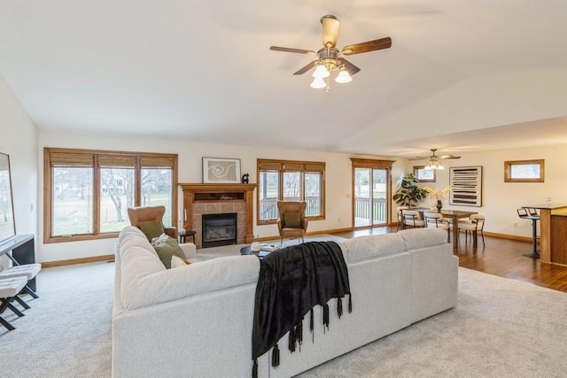 living room featuring ceiling fan, a healthy amount of sunlight, lofted ceiling, and a tile fireplace