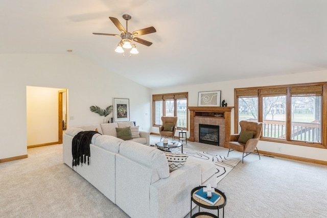 carpeted living room with a tile fireplace, vaulted ceiling, and ceiling fan