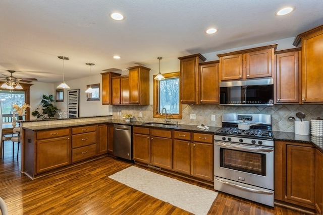 kitchen featuring ceiling fan, sink, hanging light fixtures, kitchen peninsula, and appliances with stainless steel finishes