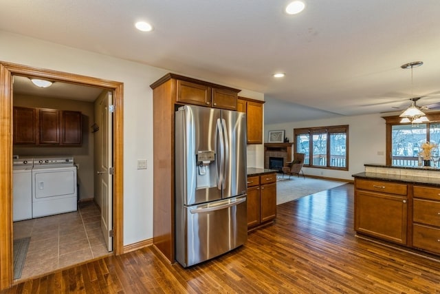 kitchen with washing machine and dryer, stainless steel fridge with ice dispenser, dark hardwood / wood-style flooring, and ceiling fan