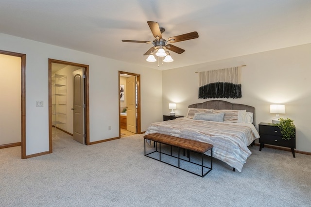 bedroom with connected bathroom, ceiling fan, light colored carpet, and a spacious closet