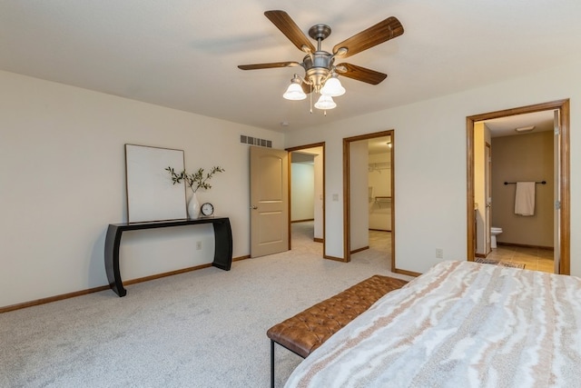 bedroom featuring ceiling fan, light colored carpet, a spacious closet, and ensuite bath