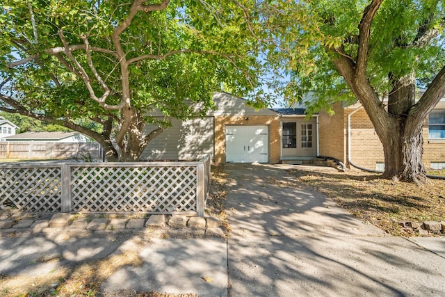 view of front of home featuring a garage, brick siding, concrete driveway, and fence