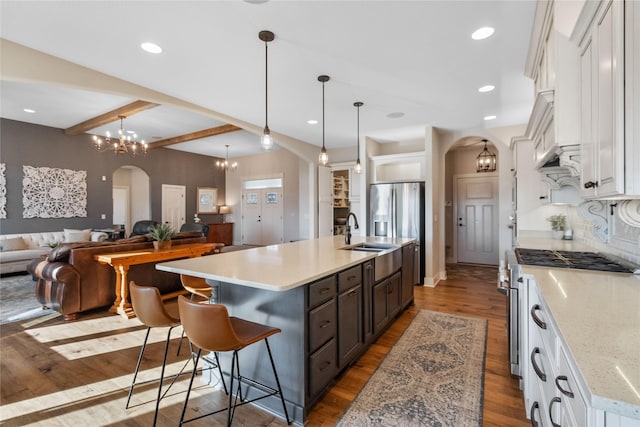 kitchen featuring white cabinets, beamed ceiling, and an island with sink