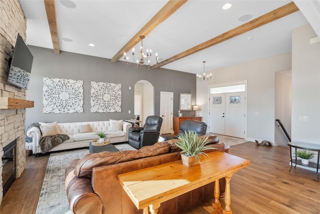 living room featuring an inviting chandelier, a fireplace, wood-type flooring, and beamed ceiling