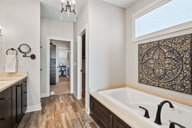 bathroom featuring hardwood / wood-style flooring, a chandelier, a washtub, and vanity