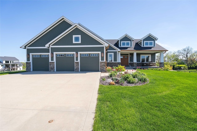9441 Coneflower Cir, Norwalk, IA 50211 - craftsman house featuring a front lawn, an attached garage, driveway, covered porch, and stone siding