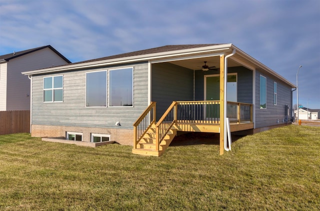 rear view of property featuring ceiling fan and a yard