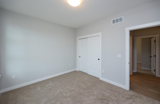 unfurnished bedroom featuring light colored carpet and a closet