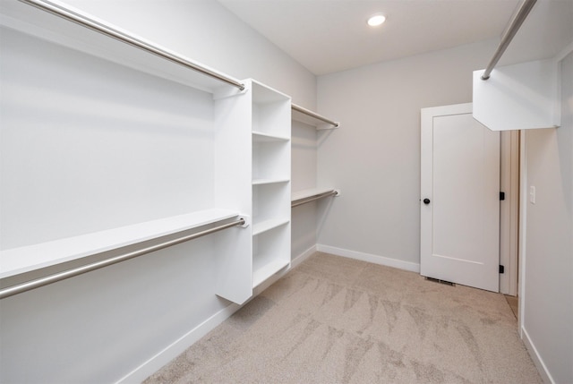 walk in closet with light carpet