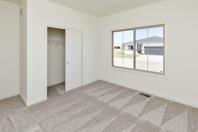 unfurnished bedroom featuring light colored carpet and a closet