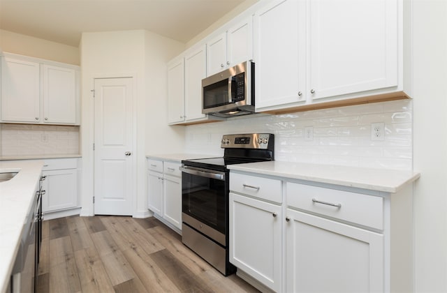 kitchen with light wood-type flooring, white cabinetry, backsplash, and appliances with stainless steel finishes