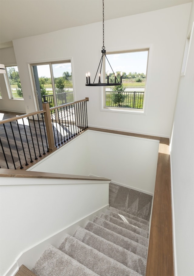 stairs featuring wood-type flooring and a notable chandelier