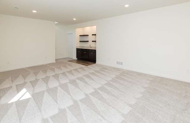 unfurnished living room with light carpet and sink