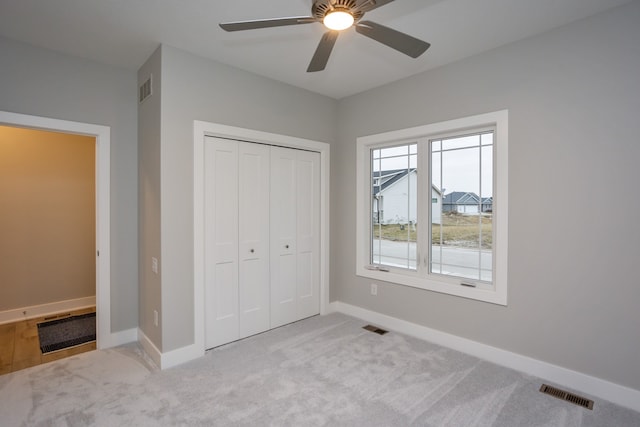 unfurnished bedroom with ceiling fan, a closet, and light colored carpet