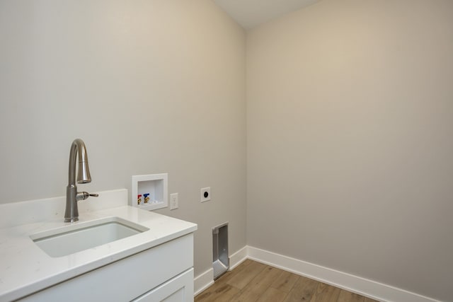 clothes washing area with sink, washer hookup, cabinets, hookup for an electric dryer, and light hardwood / wood-style flooring