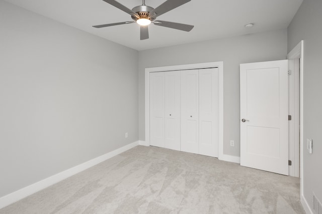 unfurnished bedroom featuring a closet, light colored carpet, and ceiling fan