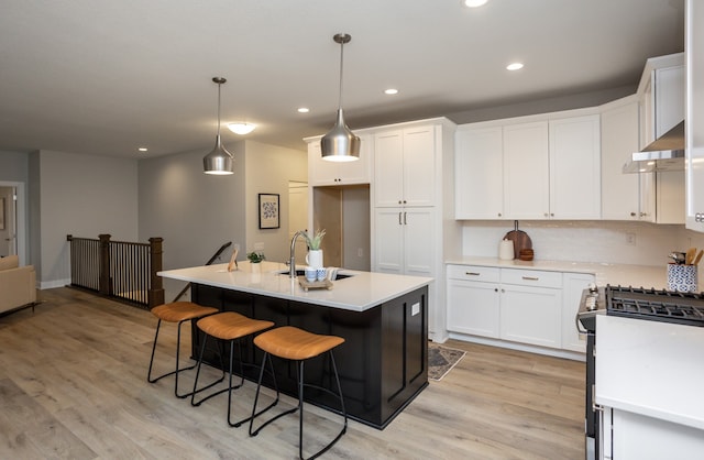 kitchen featuring white cabinets, light wood-type flooring, an island with sink, and sink