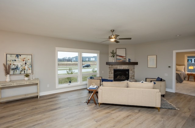 living room featuring a fireplace, ceiling fan, and light hardwood / wood-style flooring