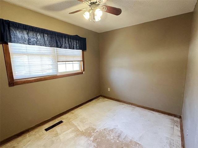 spare room featuring a textured ceiling, a ceiling fan, visible vents, and baseboards