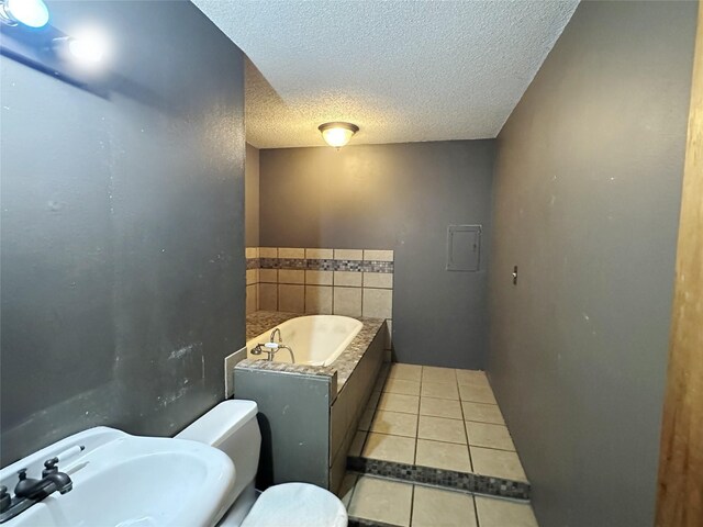 bathroom featuring a textured ceiling, tile patterned flooring, toilet, a sink, and a bath