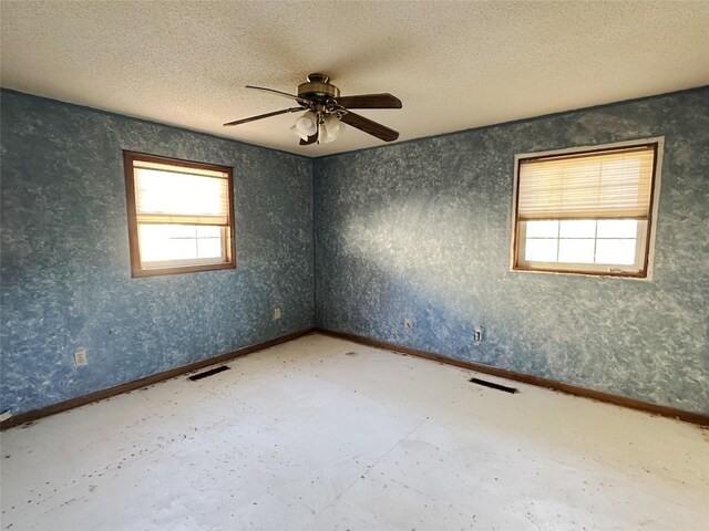 spare room featuring visible vents, ceiling fan, a textured ceiling, and baseboards