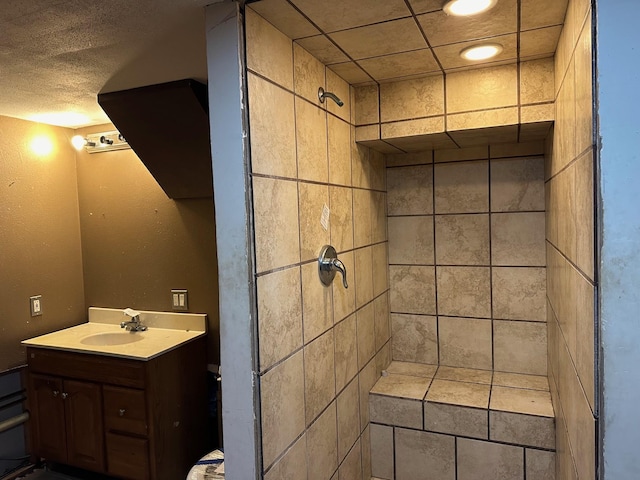 bathroom featuring tiled shower, vanity, and a textured ceiling