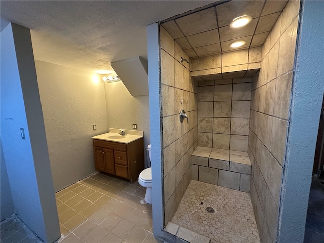 full bathroom featuring toilet, a stall shower, a textured wall, and vanity