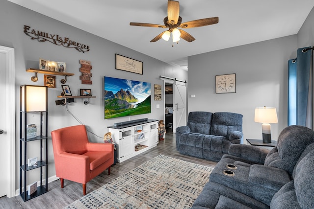 living room with a barn door, ceiling fan, and hardwood / wood-style flooring